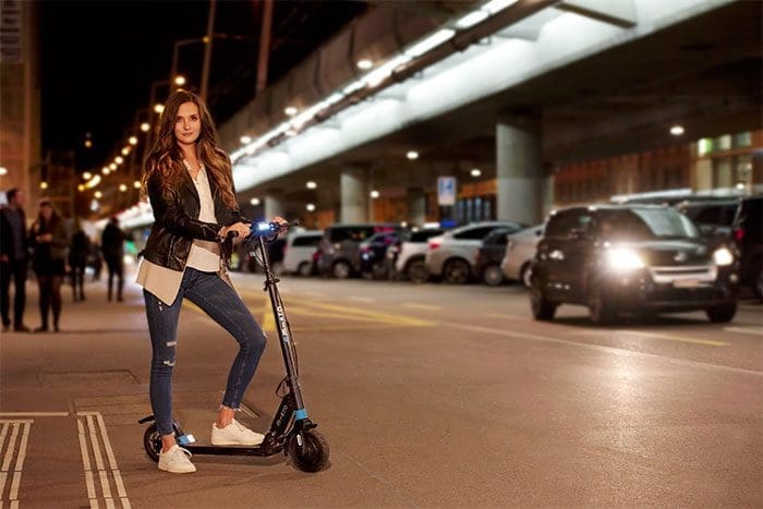 Mujer en la calle con patinete eléctrico Micro Merlín